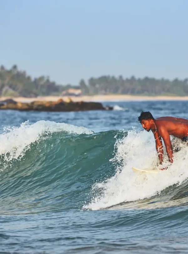 surfer rides ocean wave near tropical beach